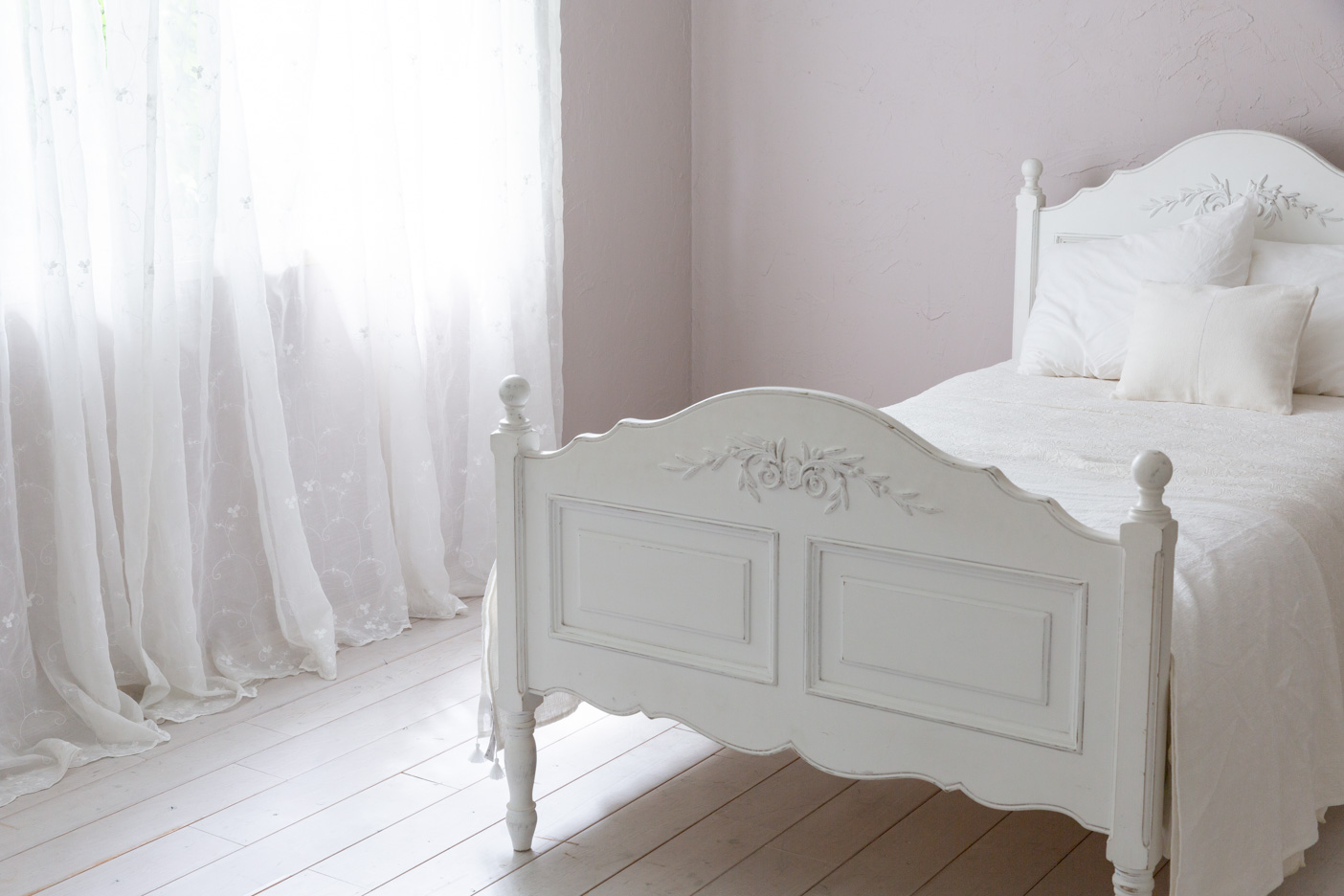 ピンクグレーの漆喰壁とロマンティックベッド